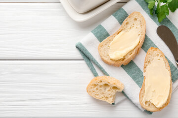 Slices of bread with butter on white wooden table, flat lay. Space for text