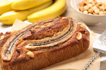 Delicious homemade banana bread with nuts, server and fruits on table, closeup