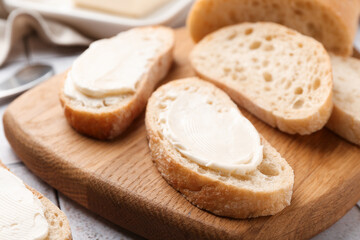 Pieces of bread with butter on light tiled table, closeup
