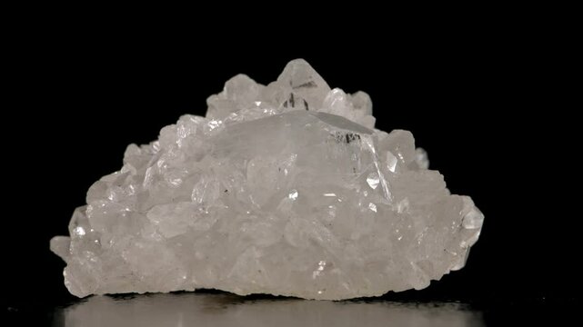 White Apophyllite cluster  of crystals rotating slowly against a black background