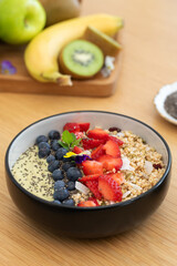 Healthy breakfast avocado smoothie bowl with fresh fruits and chia seeds on wooden table