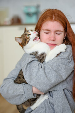 Cute chaos: girl laughs as her cat pushes her away mid-hug, classic love-hate pet moment