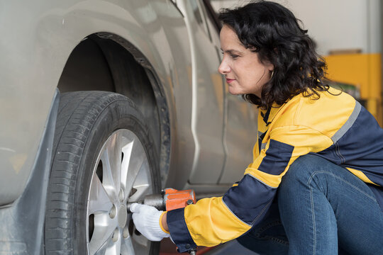 Woman, car mechanic working on engines as mechanic in garage for repair, maintenance and vehicle service. Mechanic inspecting and changing wheel by air impact wrench