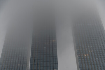 Fog envelops skyscrapers in a misty urban setting at dawn
