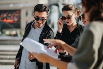 A team of business people, wearing sunglasses, reviews documents together outdoors. The scene conveys collaboration and teamwork in a modern business environment.