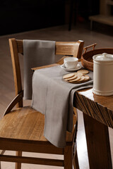 grey cotton towels and napkins on a wooden table and on the back of a chair, tea party, kitchen, dining room