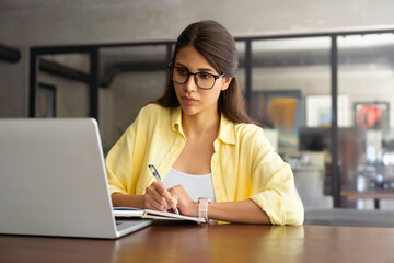 Focused young female woman student watching webinar video conference online for studying. Latin...