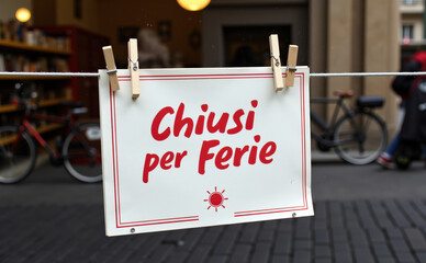 the sign displays "chiusi per ferie" indicating the establishment is closed for holidays, with bicycles in the background giving a casual, local vibe