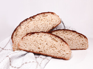 Freshly baked round bread cut into slices on a white background. Close up.