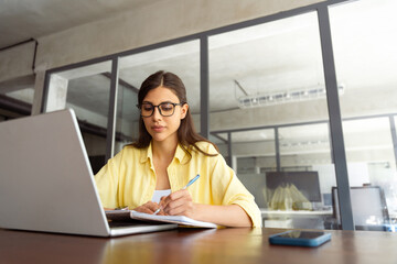 Focused young female woman student watching webinar video online for studying. Latin hispanic girl...