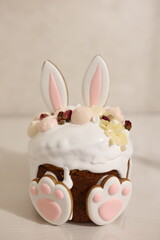 Easter cake decorated with white icing, almonds, meringues, dried roses, and bunny-shaped cookies with ears and paws. A festive and adorable holiday dessert perfect for spring celebrations.