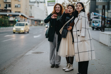 Obraz premium Women stand together on a city street, smiling and engaging in conversation. The urban backdrop adds a modern and casual atmosphere, highlighting their fashion, friendship, and dynamic interaction.
