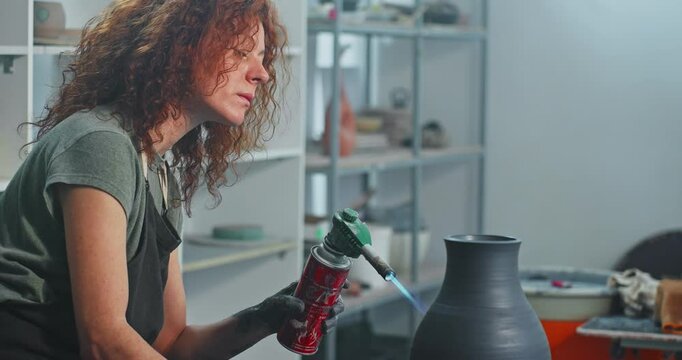 Crafting a stunning clay vase in a pottery studio using a torch for finishing touches