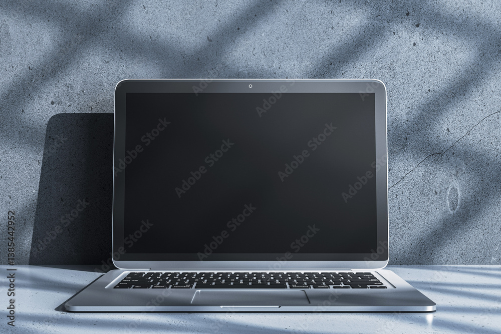 Aufkleber blank laptop screen mockup on concrete surface with dramatic shadows, ideal for modern presentation,