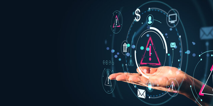 Businessperson holding digital warning icons in hand with technology interface on dark background, representing data risk concept in business.