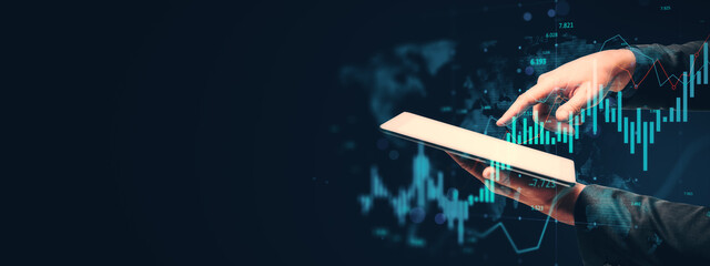 Businessperson using tablet with financial data and digital chart overlay on dark background symbolizing technology-driven business analysis..