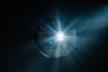 Disco ball in a dark room with smoke. Bright rays from a disco ball. Party, style and decor concept.