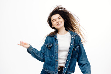 Energetic, stylish girl dancing on white background. Long hair fluttering from the movement. Concept of style, fashion, entertainment and recreation.