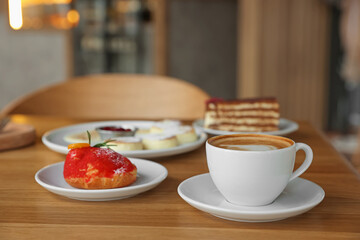 Aromatic coffee and delicious desserts served on wooden table in cafe