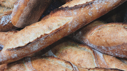 A stack of bread loaves with a few of them being slightly burnt. The bread is brown and has a crispy texture