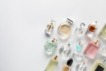 Bottles of various perfumes on light background, flat lay. Space for text
