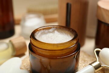 Different body care products and massaging tools on beige background, closeup