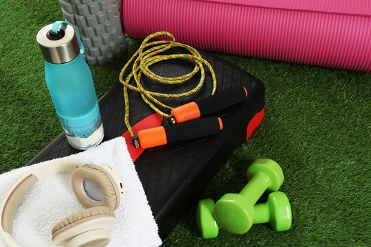 Different fitness equipment and headphones on green grass