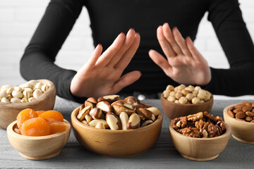 Woman refusing to eat products at grey wooden table, selective focus. Food allergy concept