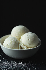 Natural healthy ice cream scoops in a bowl against a dark background  