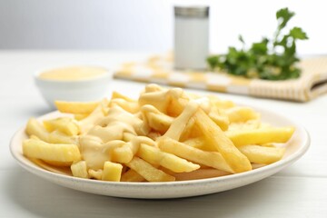 French fries with cheese sauce on white wooden table, closeup