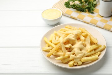 French fries with cheese sauce and parsley on white wooden table, closeup. Space for text