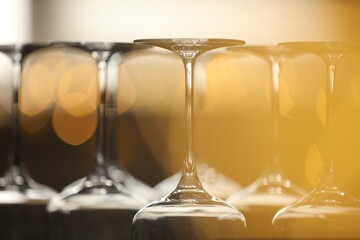 Upturned empty clean glasses on blurred background, closeup. Bokeh effect