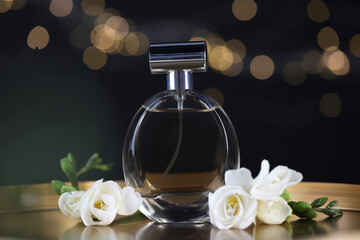 Bottle of aromatic perfume and flowers on metal tray against black background with blurred lights,...