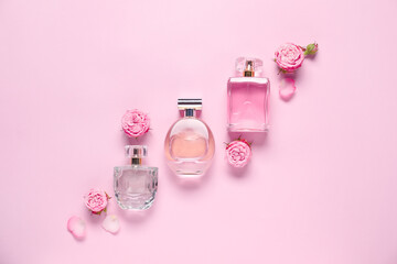 Bottles of perfume and beautiful flowers on pink background, flat lay