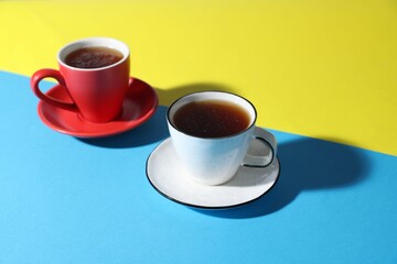 Cups with aromatic coffee drinks on color background, closeup