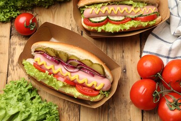 Tasty hot dogs with vegetables on wooden table, flat lay