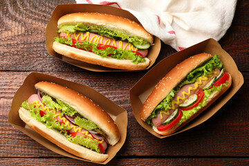 Tasty hot dogs with vegetables on wooden table, flat lay