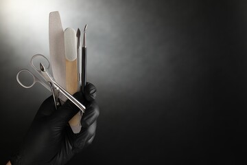 Woman with manicure tools on black background, closeup. Space for text
