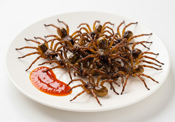 Obraz premium Fried Spiders on a White Plate with Red Sauce