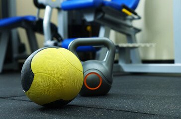 Yellow medicine ball and kettlebell on floor in gym, space for text