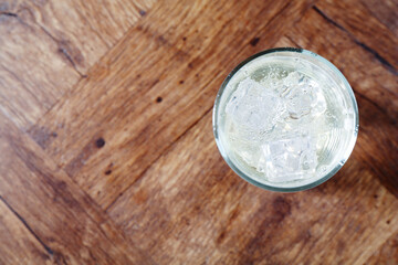 Refreshing soda water with ice cubes in glass on wooden table, top view. Space for text