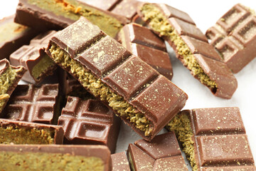 Pieces of tasty Dubai chocolate with pistachios and knafeh on white table, closeup