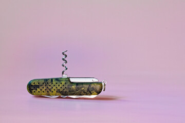 A multitool with a corkscrew extended, ready to open bottles. The pink and purple background...