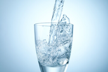 Pouring refreshing soda water into glass on light background, closeup