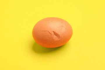 One egg with cracked shell on yellow background