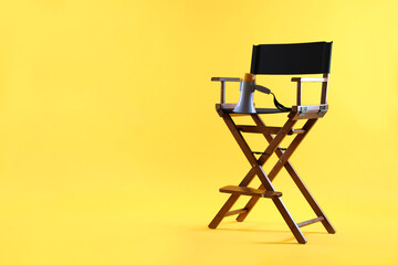Fototapeta premium Director's chair with megaphone on yellow background, space for text