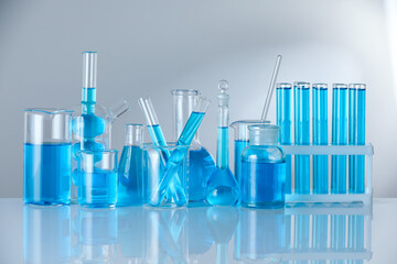 Laboratory glassware with blue liquid on mirror surface against grey background
