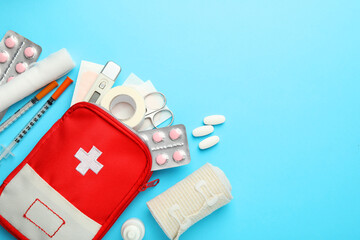 Flat lay composition with first aid kit on light blue background, space for text