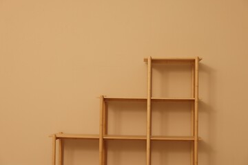 Empty shelving unit near beige wall indoors, space for text