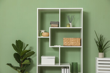 Wooden shelving unit with different home decor near olive wall indoors